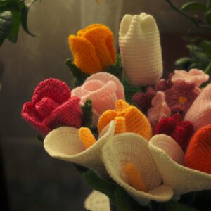 A vibrant bouquet of crocheted flowers in various colors, arranged in a vase.