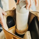 About A leather tote bag neatly packed with travel essentials including a water bottle and accessories.