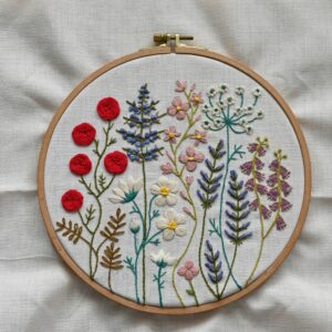 Vibrant handcrafted floral embroidery showcased in a wooden hoop on fabric.