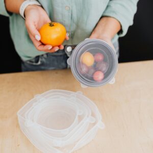 Person holding fresh vegetables and using eco-friendly storage in kitchen.