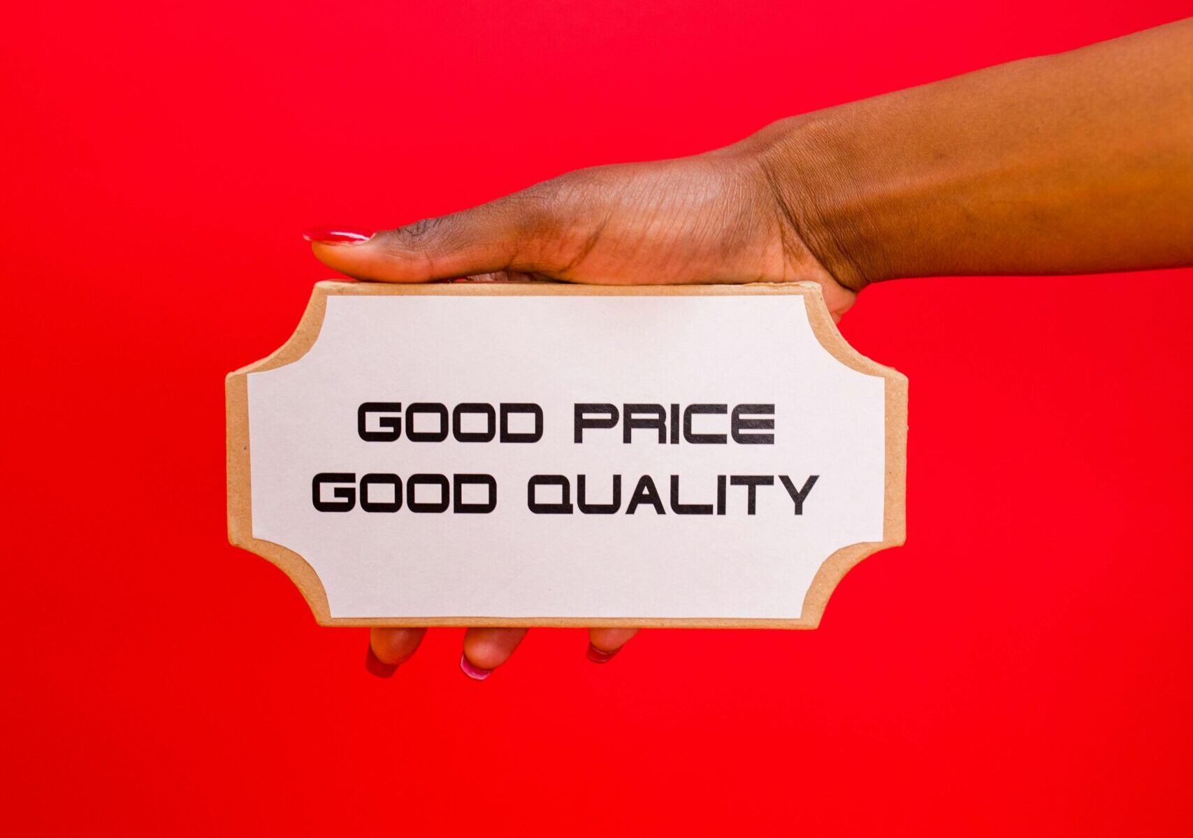 About A hand holding a sign with 'Good Price, Good Quality' text against a bright red background.
