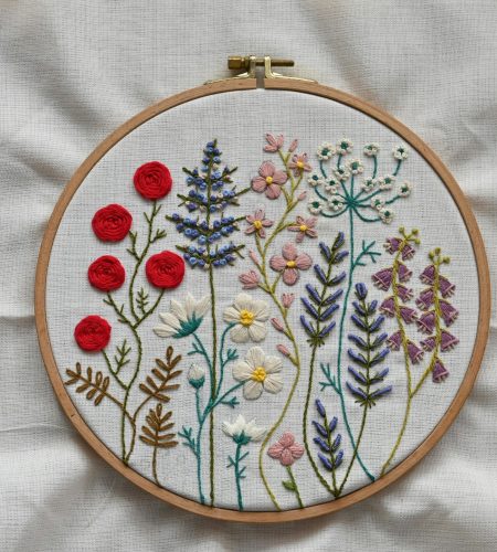 About Vibrant handcrafted floral embroidery showcased in a wooden hoop on fabric.